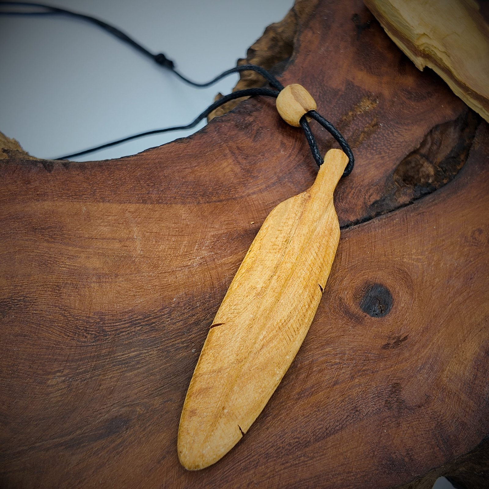 a feather shaped pendant made of natural palo santo wood that is very fragrant and considered very high frequency in spirituality for cleansing and clearing and attracting good energy